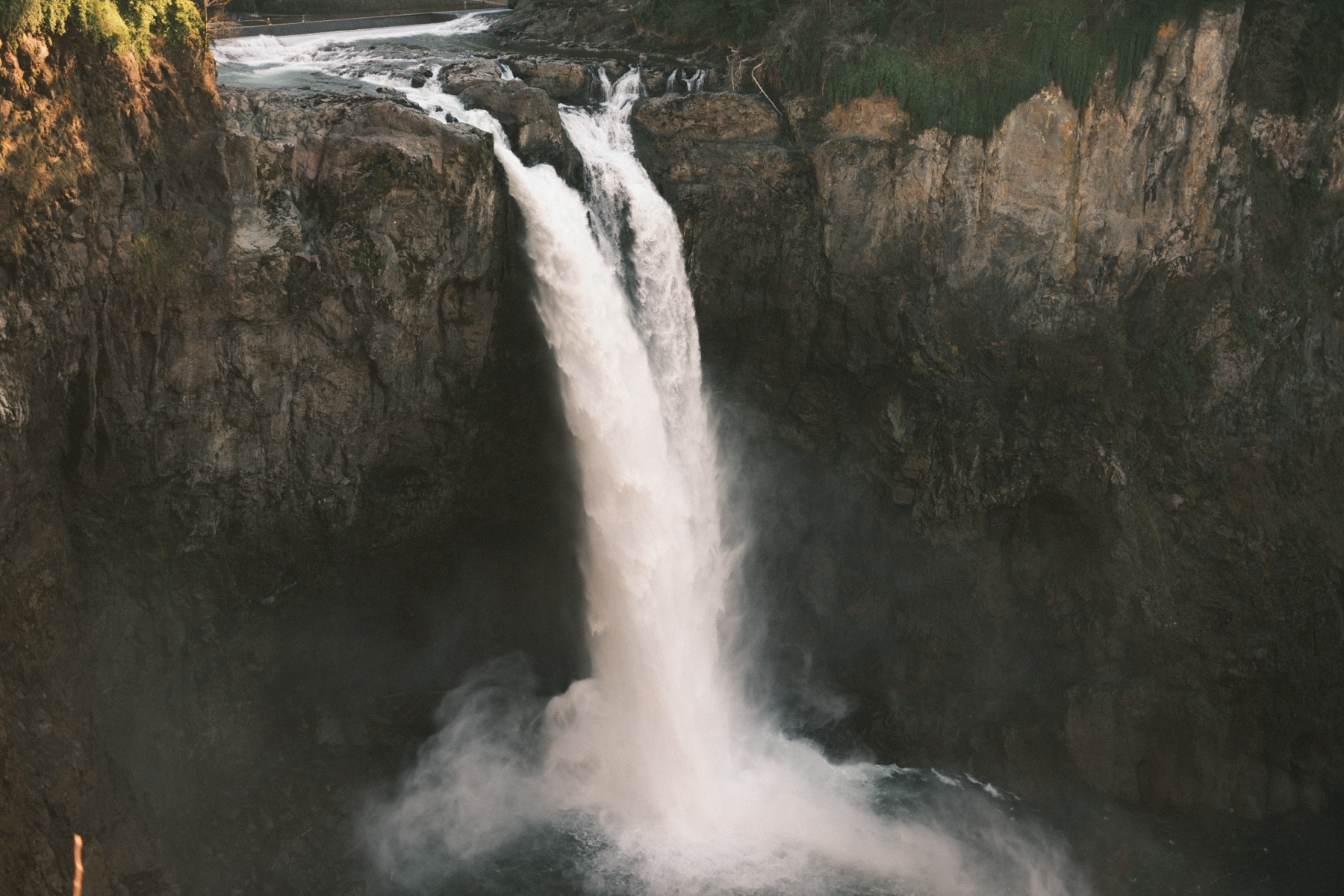 A waterfall plunging off a rocky cliff into a misty pool