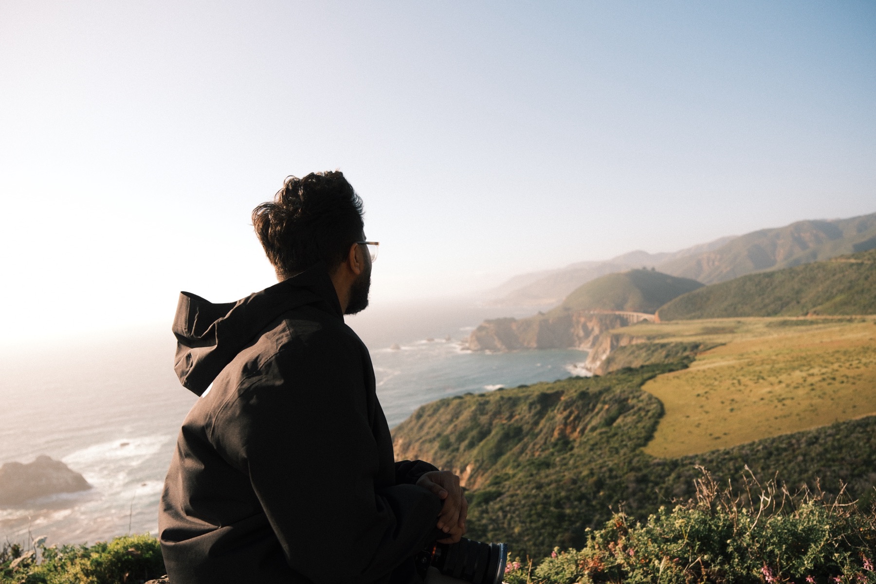 A person gazing out over the Big Sur coastline at golden hour