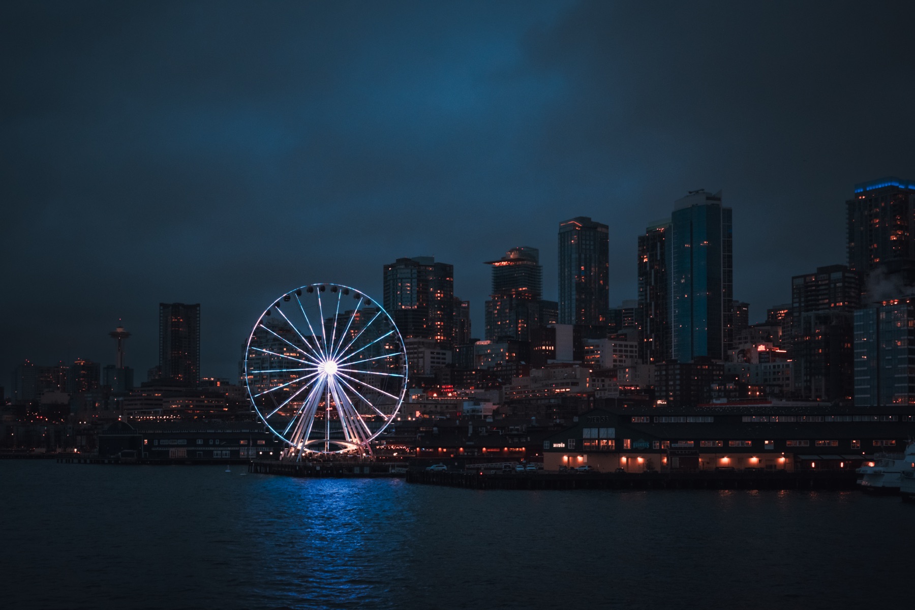 The Seattle Great Wheel lit up at night against the downtown skyline